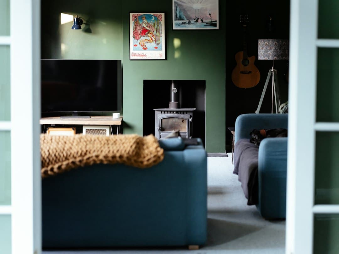 Un salon aux murs verts avec un téléviseur, un canapé bleu et un poêle, pour comprendre Xenon IPTV